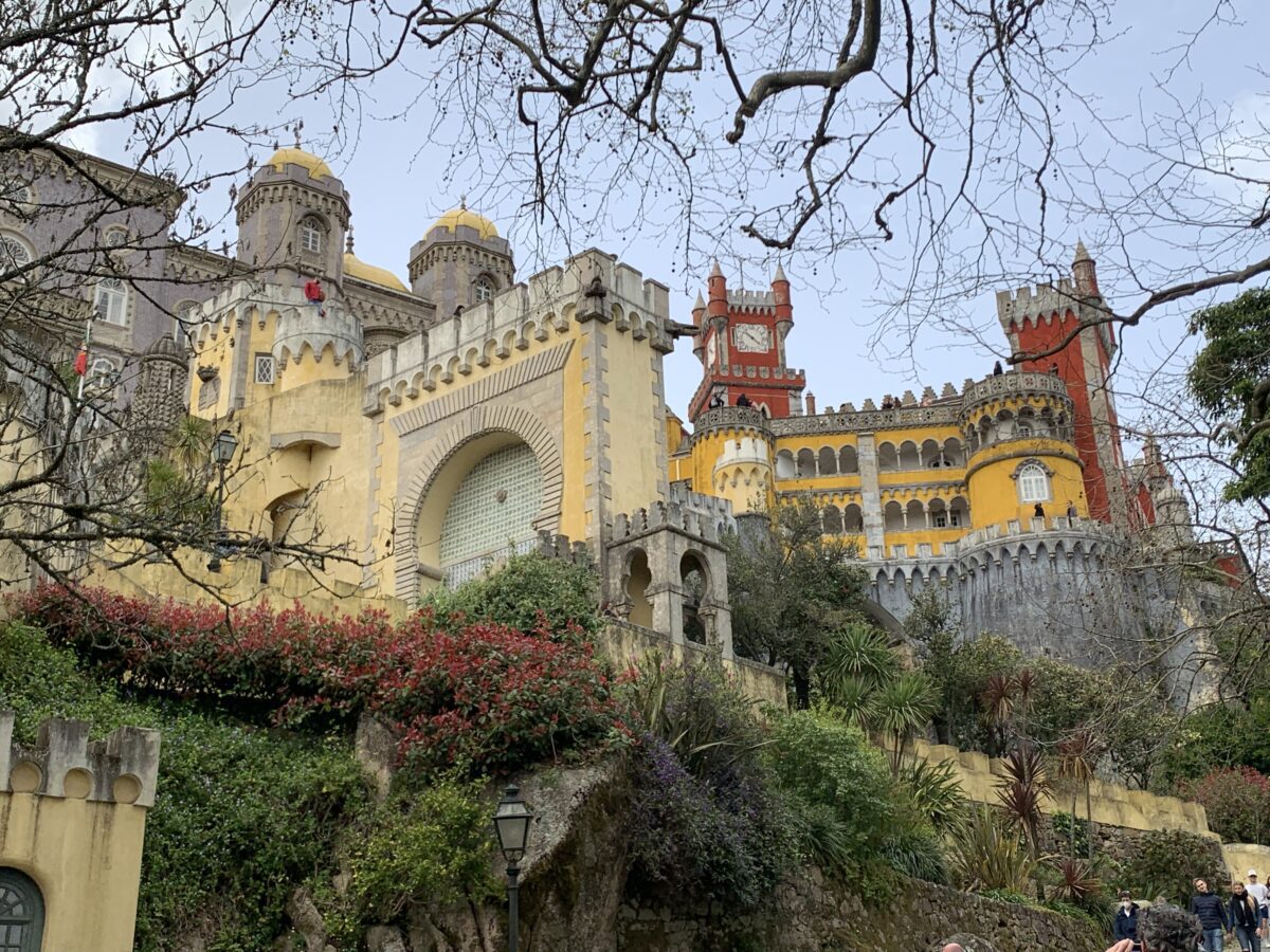 A castle sits on a stone hill with yellow, red, and purple walls