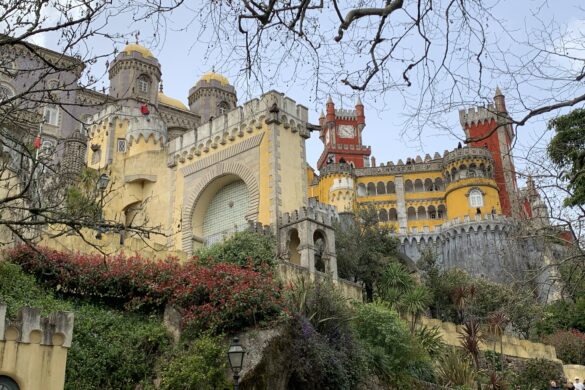 A castle sits on a stone hill with yellow, red, and purple walls