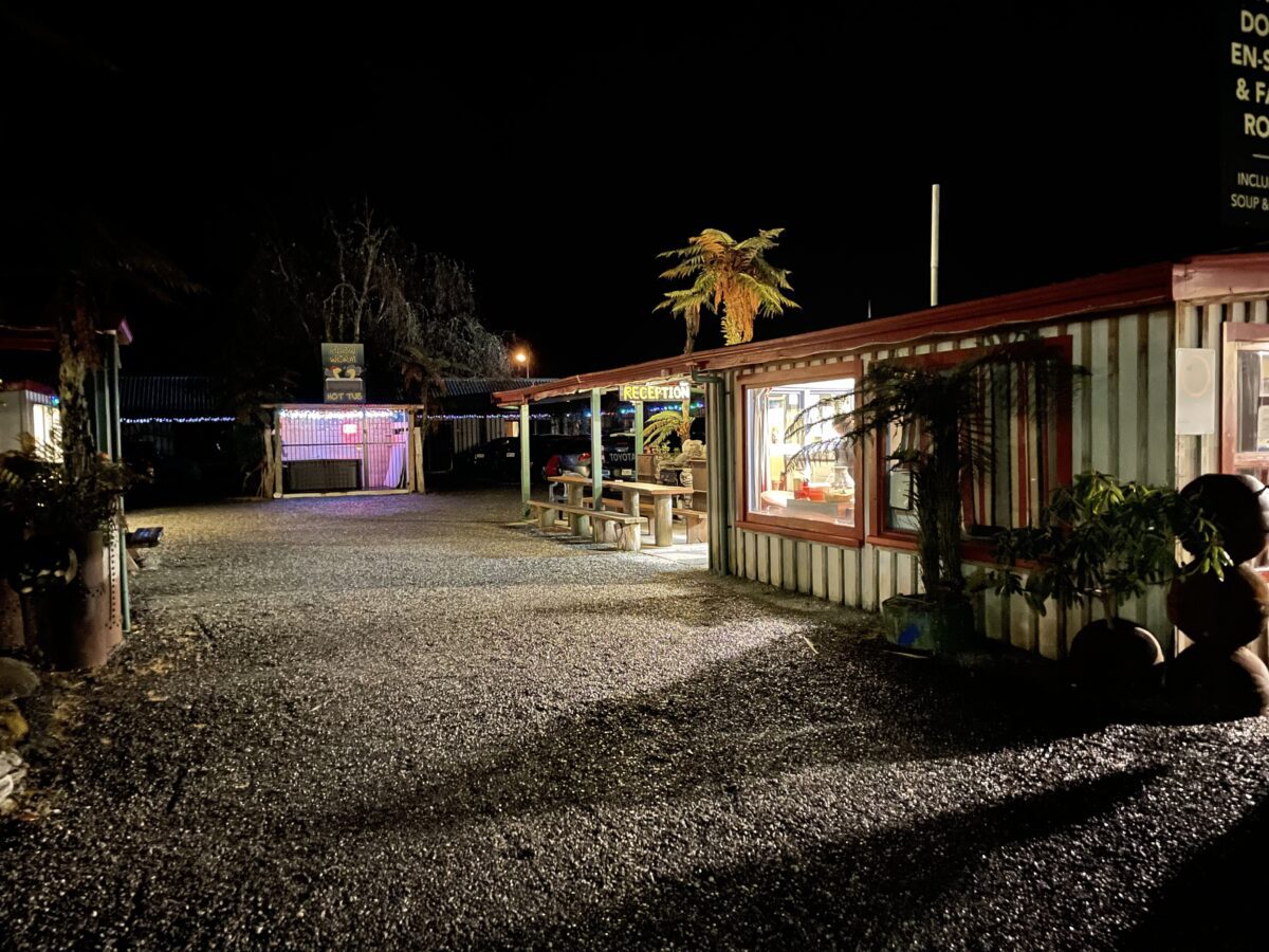 a gravel driveway at nighttime with lights illuminating a reception block
