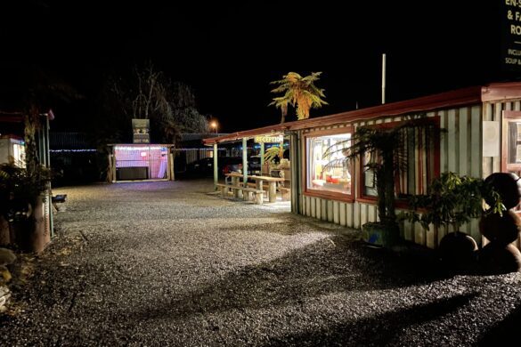 a gravel driveway at nighttime with lights illuminating a reception block