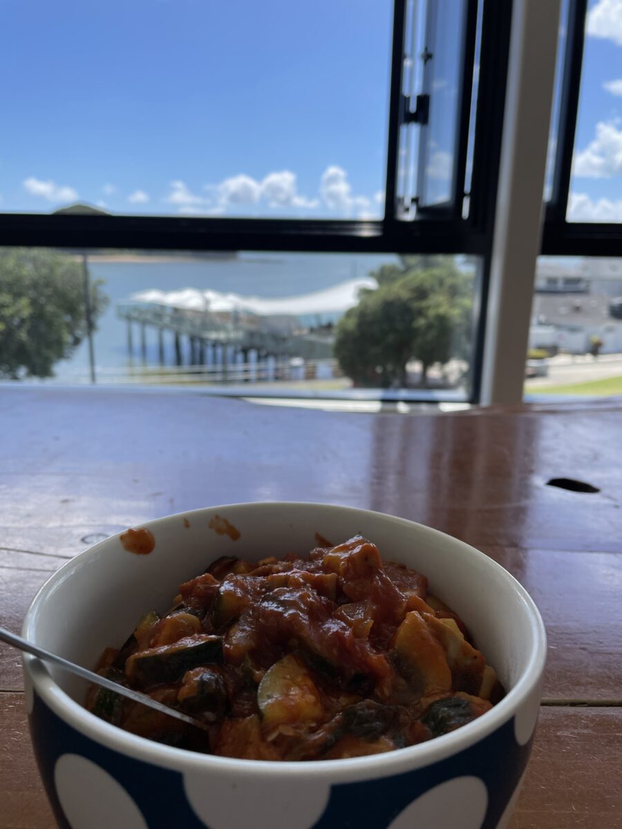 a bowl of pasta with red sauce on a table in front of a window
