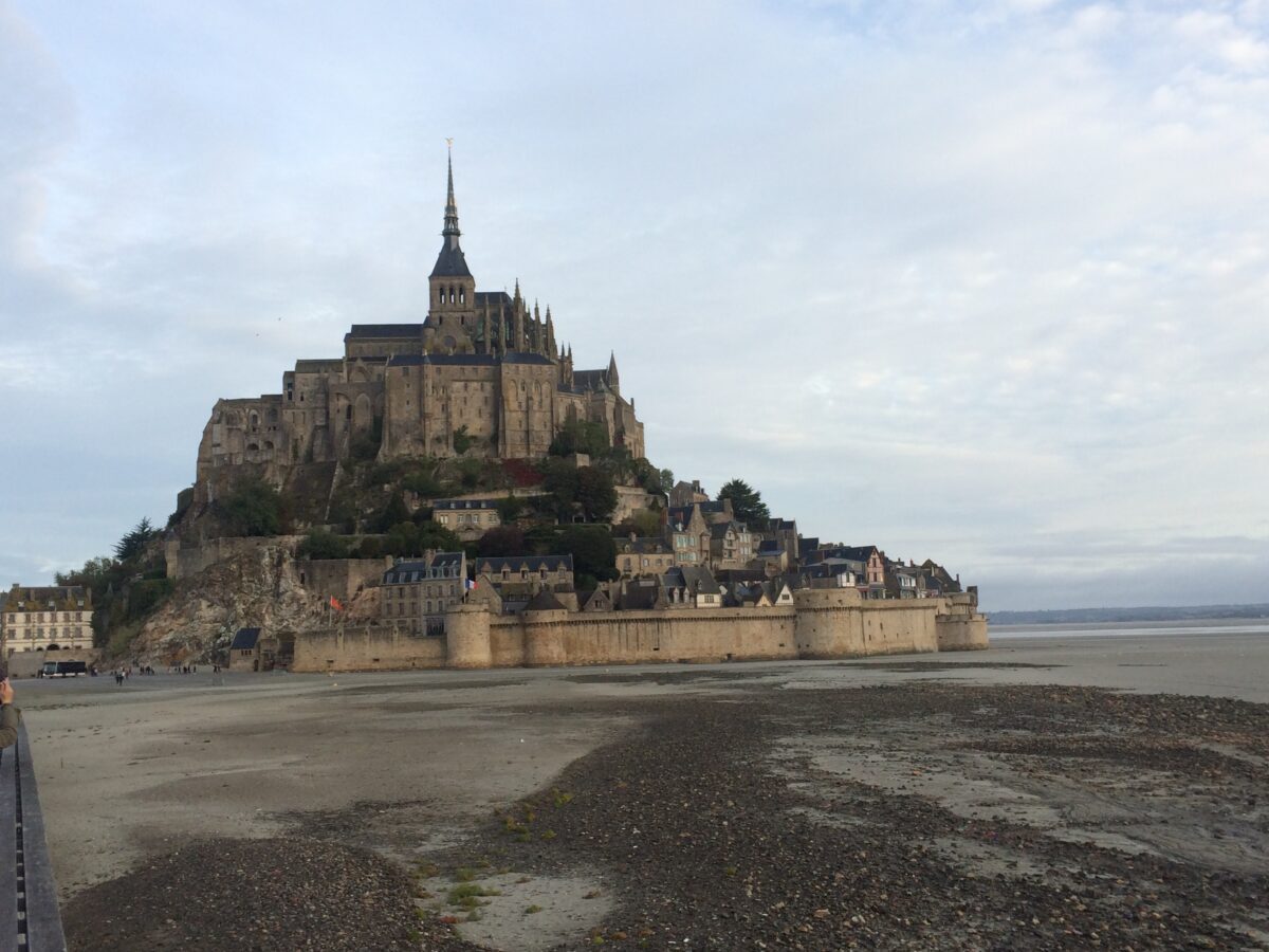 Iconic Mont St Michel island surrounded by low tide pools and wet sand