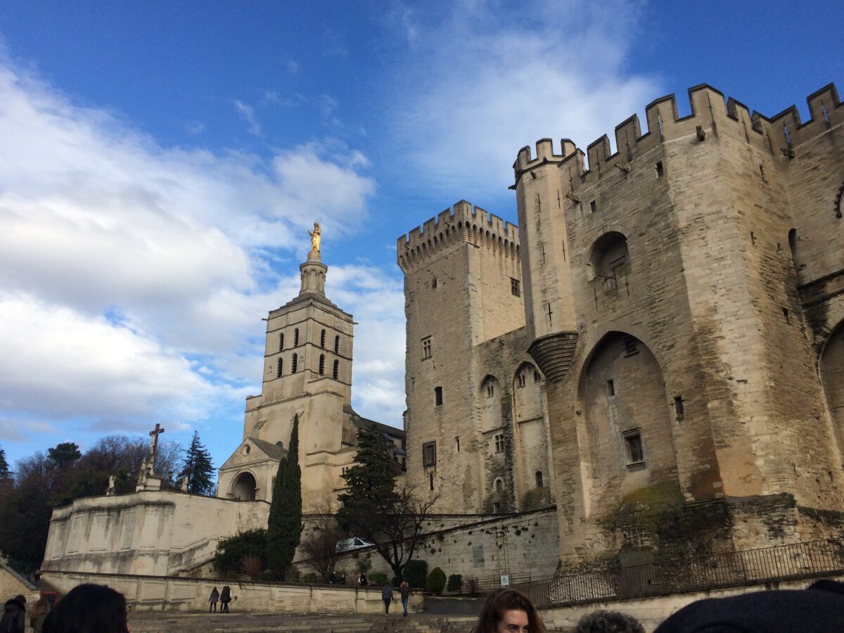 The Palais de Papes in Avignon, limestone towers with a gold statue on top