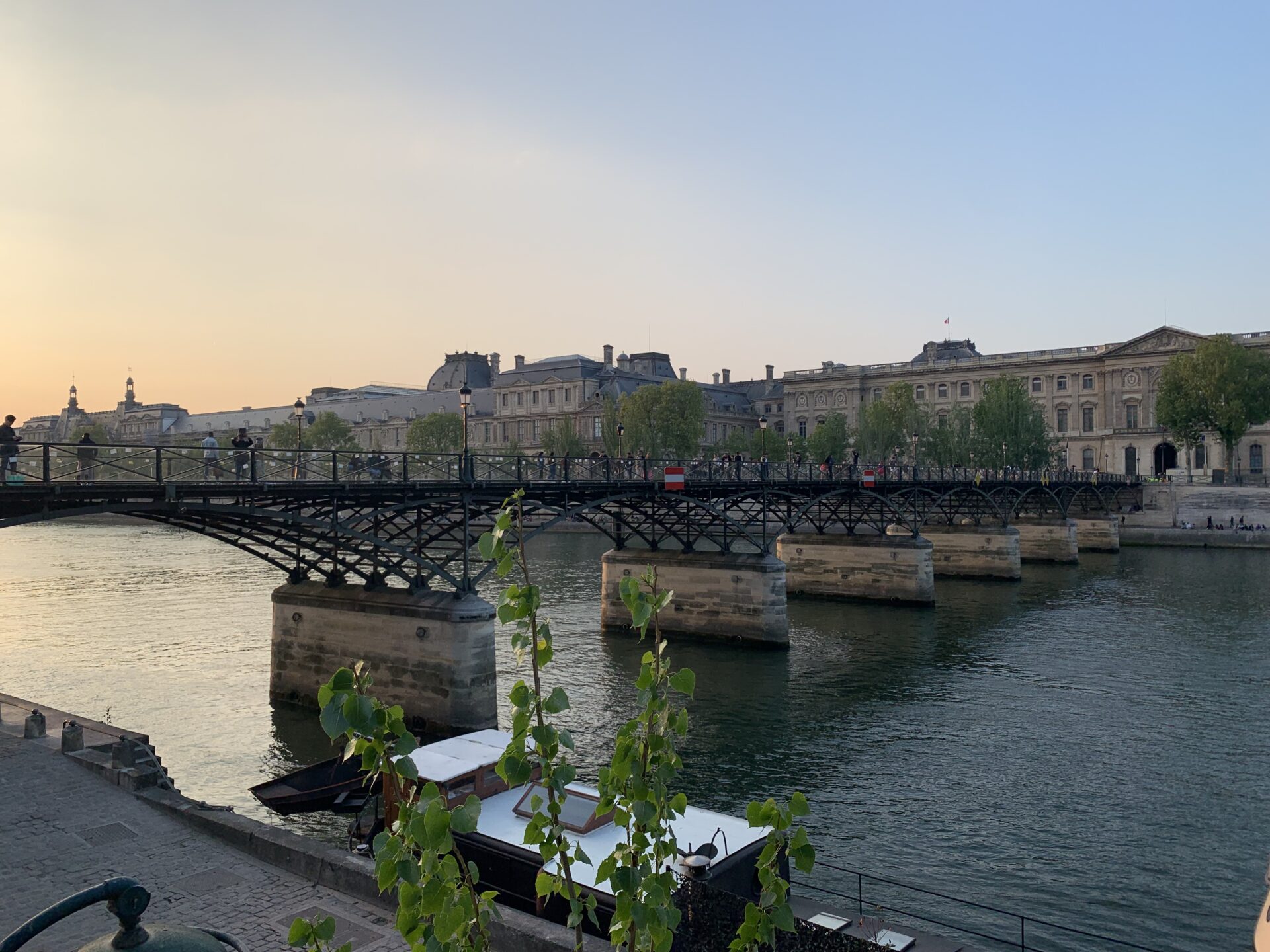 A pedestrian bridge over the river Seine at sunset
