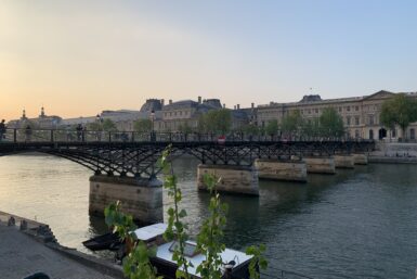 A pedestrian bridge over the river Seine at sunset