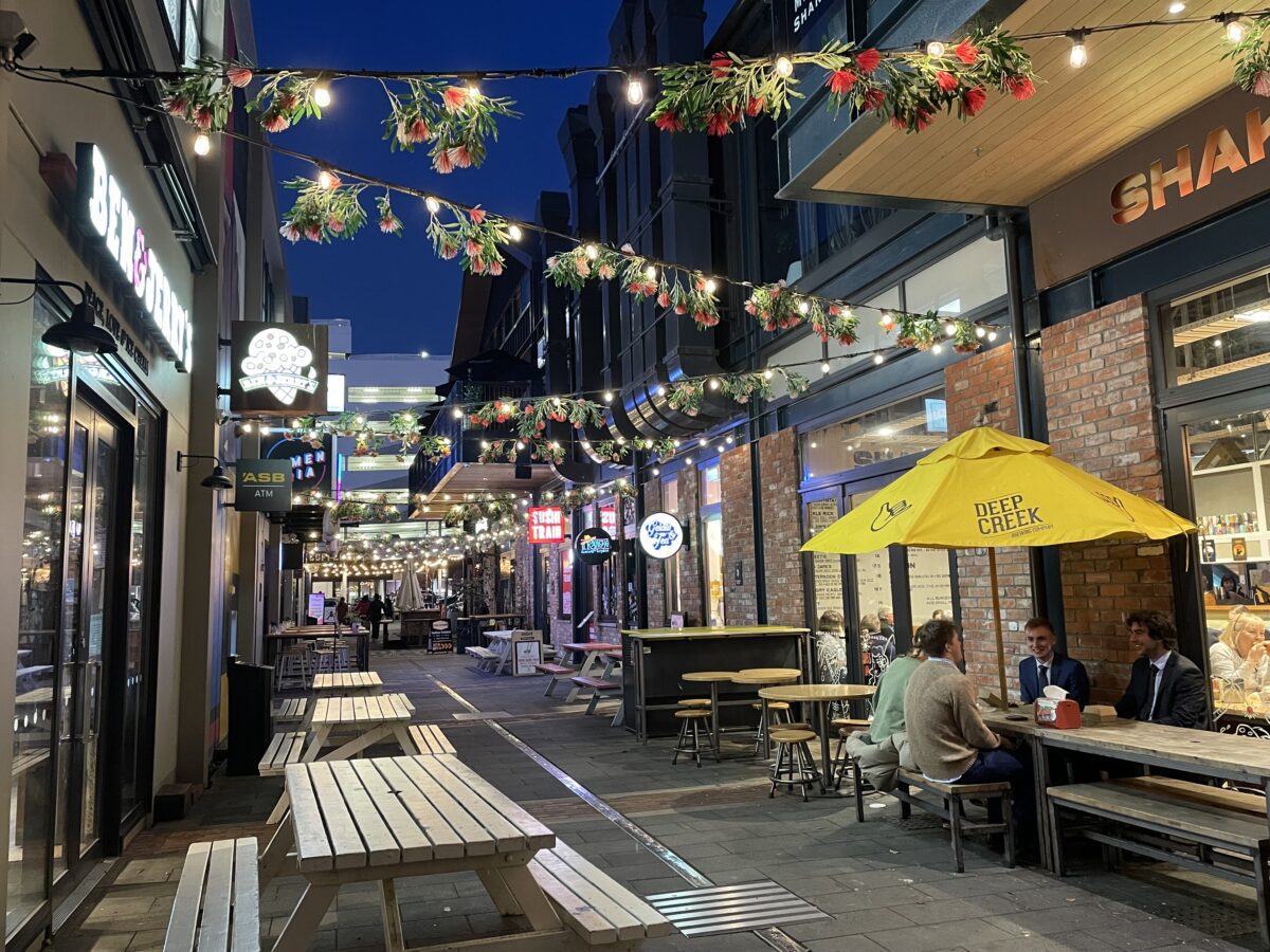 An outdoor pedestrian street with outdoor seating and fairy lights strung over the alleyway