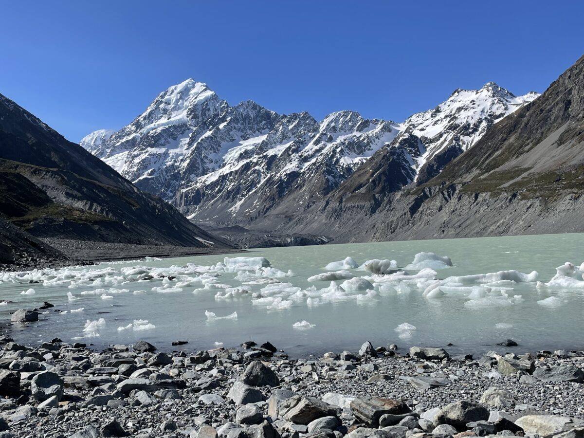 The snowy summit of Mt Cook/Aoraki with the glacier lake with chunks of ice in the foreground
