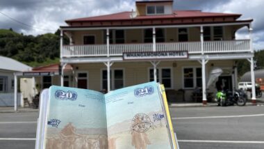 Open passport with a stamp from Whangamomona in front of the Whangamomona Hotel